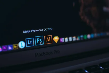 MacBook ekranında Adobe Photoshop, Lightroom ve Illustrator uygulama ikonları yakın planda görünüyor.