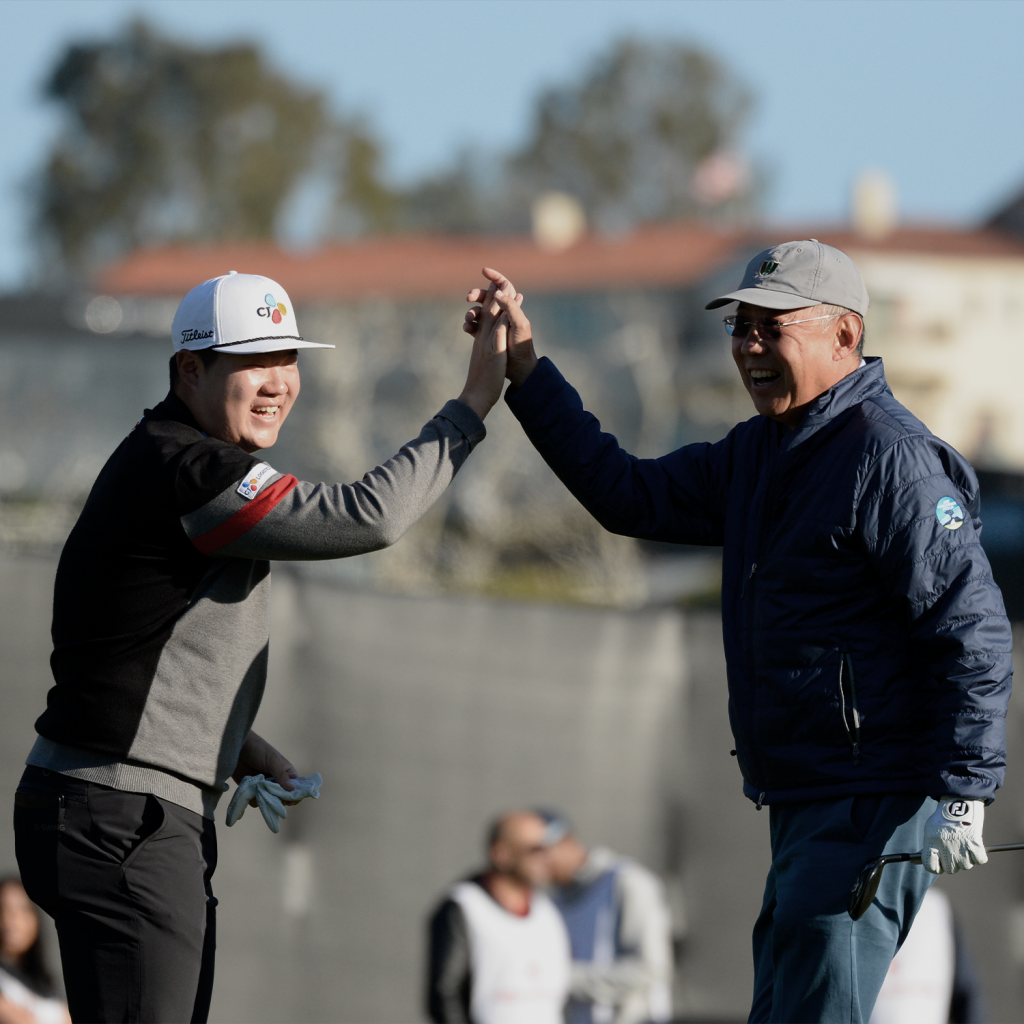 Golf sahasında iki erkek oyuncu, gülümseyerek birbirlerine çak yapıyor.