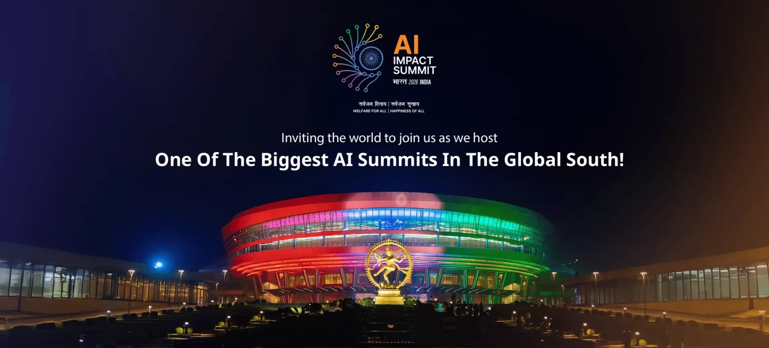 AI Impact Summit (Bharat 2026 India) tanıtım görseli; “One Of The Biggest AI Summits In The Global South!” yazısı ve gece ışıklandırılmış, renkli bir kongre/arena binası önünde heykel.
